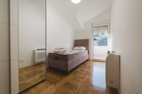Smaller bedroom with a bed, large mirror, and access to the terrace. - image 6