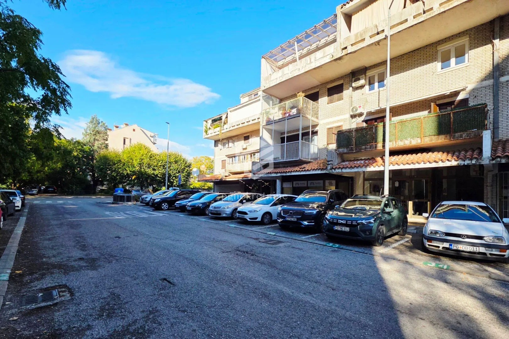 Pogled na spoljašnjost zgrade i parking ispred ulaza.