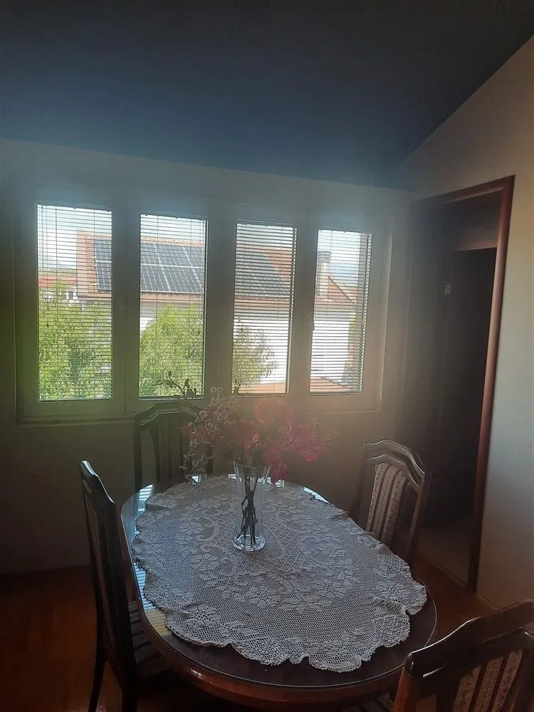 A dining table with chairs placed next to a window with blinds.