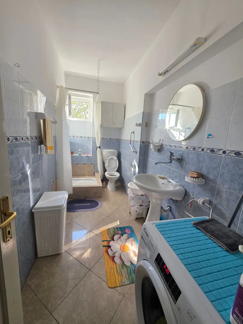 Bright bathroom with a bathtub, washbasin, and washing machine.