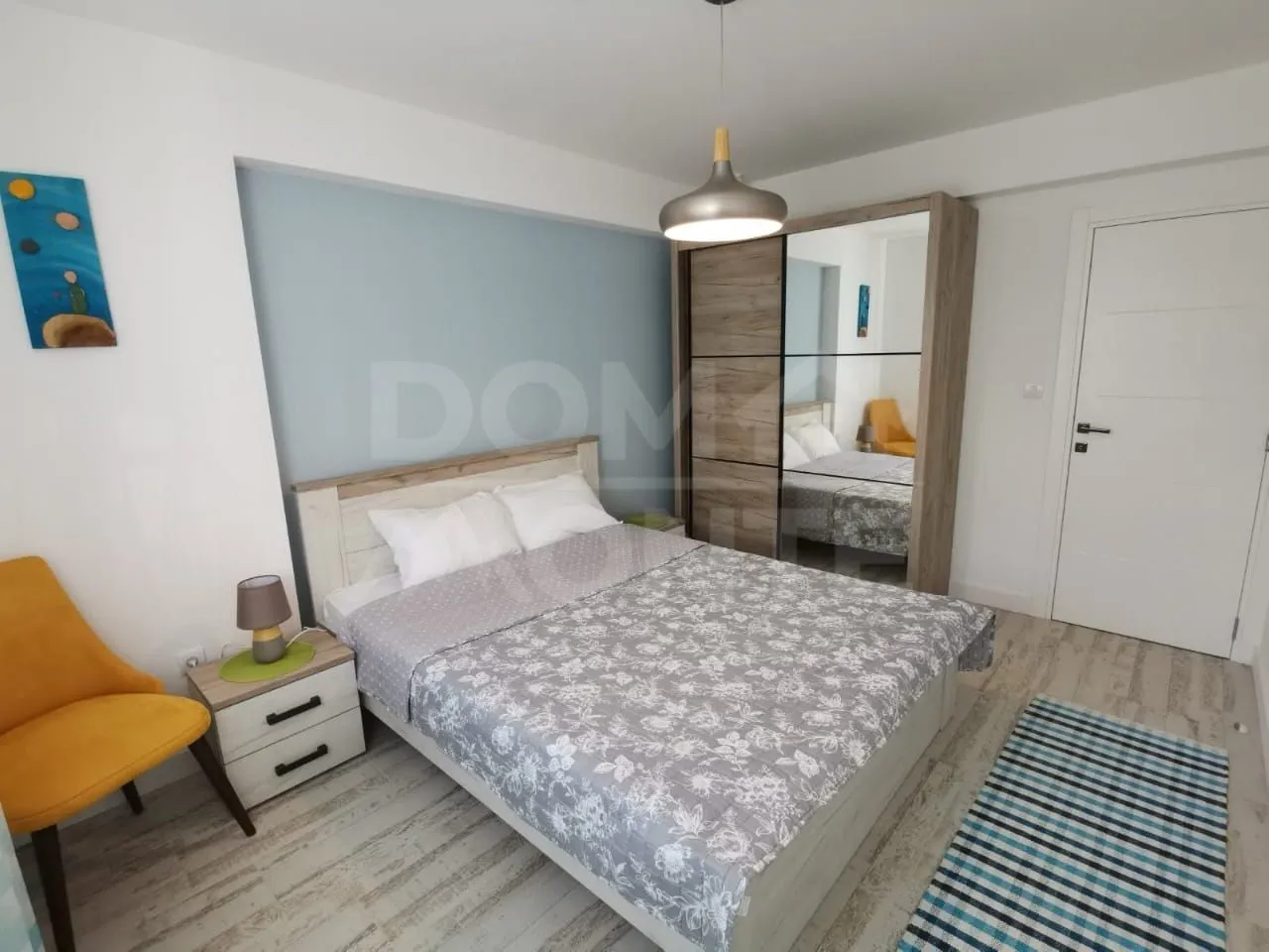 Furnished bedroom with a double bed, wardrobe, and nightstand.