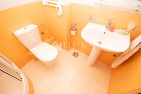 Compact bathroom with a washbasin, toilet, and shower cabin tiled in orange tiles. - image 7