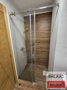 Moderna tuš kabina sa staklenim paravanom i keramičkim pločicama u dezenu drveta. - image 6
