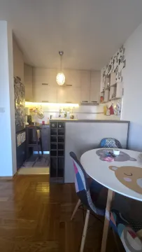 Dining area with a round table and a view of the kitchen. - image 3