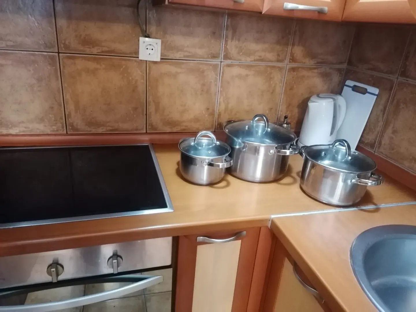 Dio kuhinje sa radnom pločom, šporetom i sudoperom.