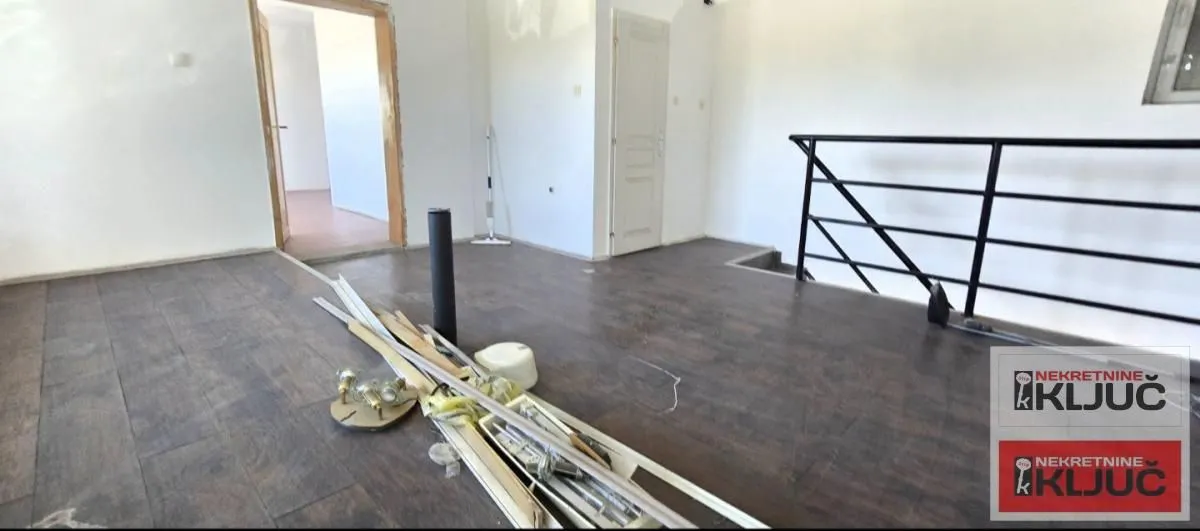 Empty room with dark laminate flooring and construction materials on the floor.