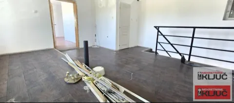 Empty room with dark laminate flooring and construction materials on the floor. - image 10