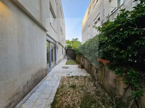 Bočni dio dvorišta zgrade sa popločanim stazama i zelenilom. - image 5