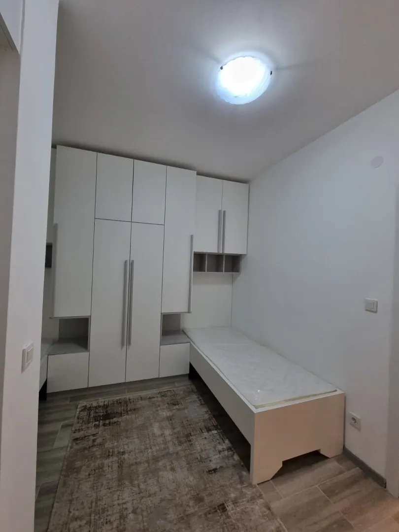 A small bedroom with a white built-in wardrobe and a single bed.
