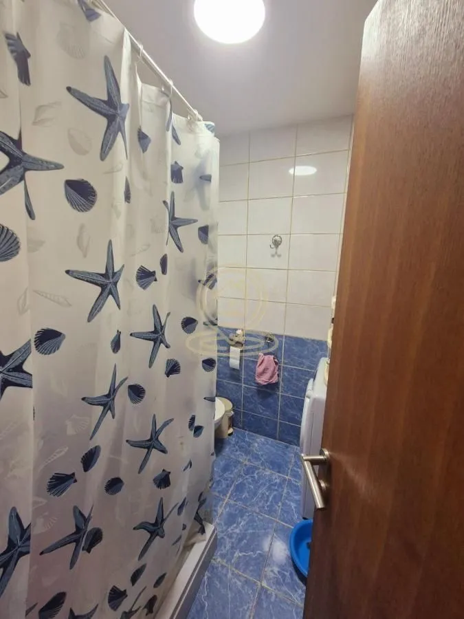 Pogled na kupatilo sa tuš kabinom i plavim pločicama.