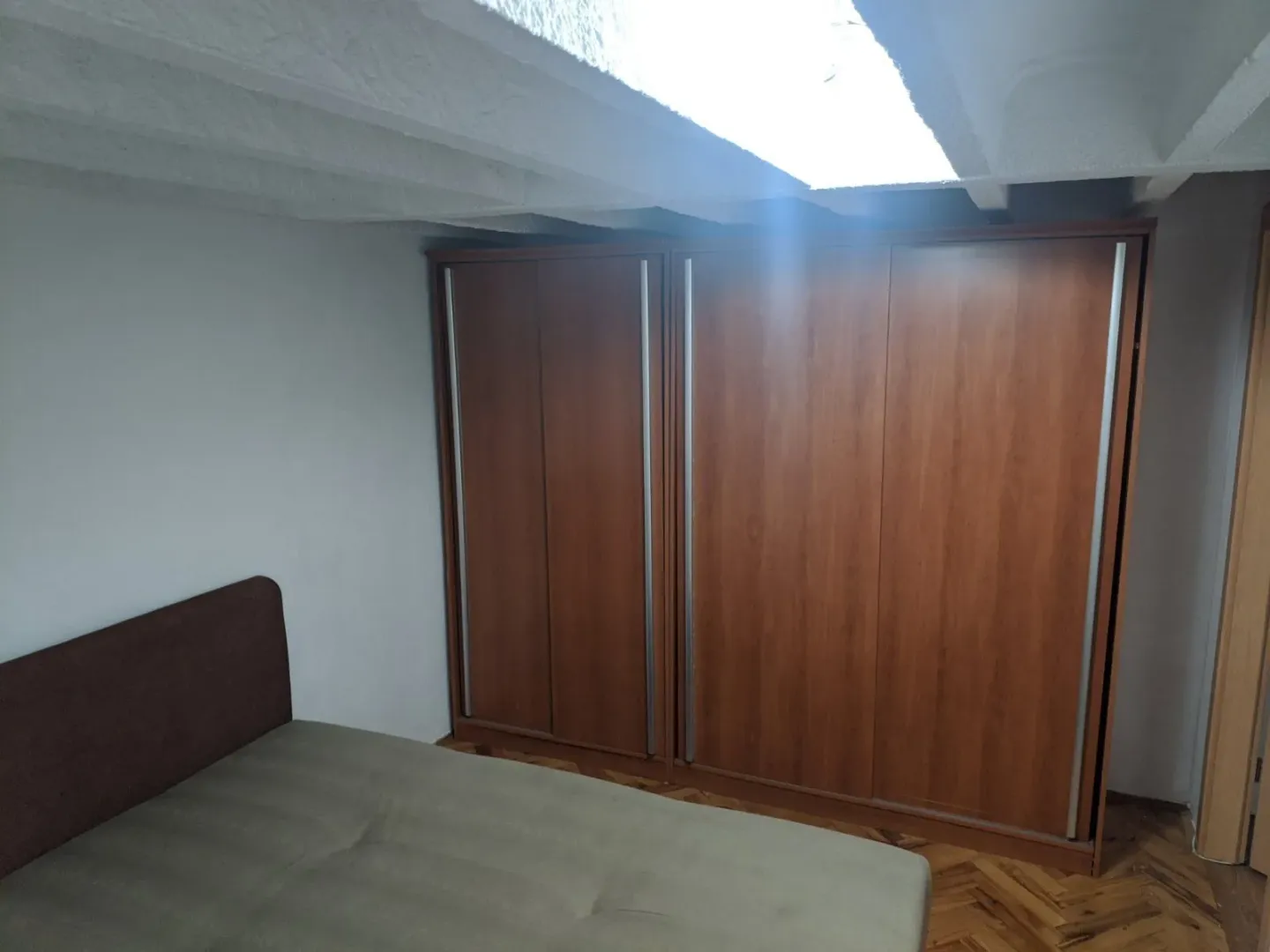 A bedroom featuring a large wooden wardrobe and a bed.