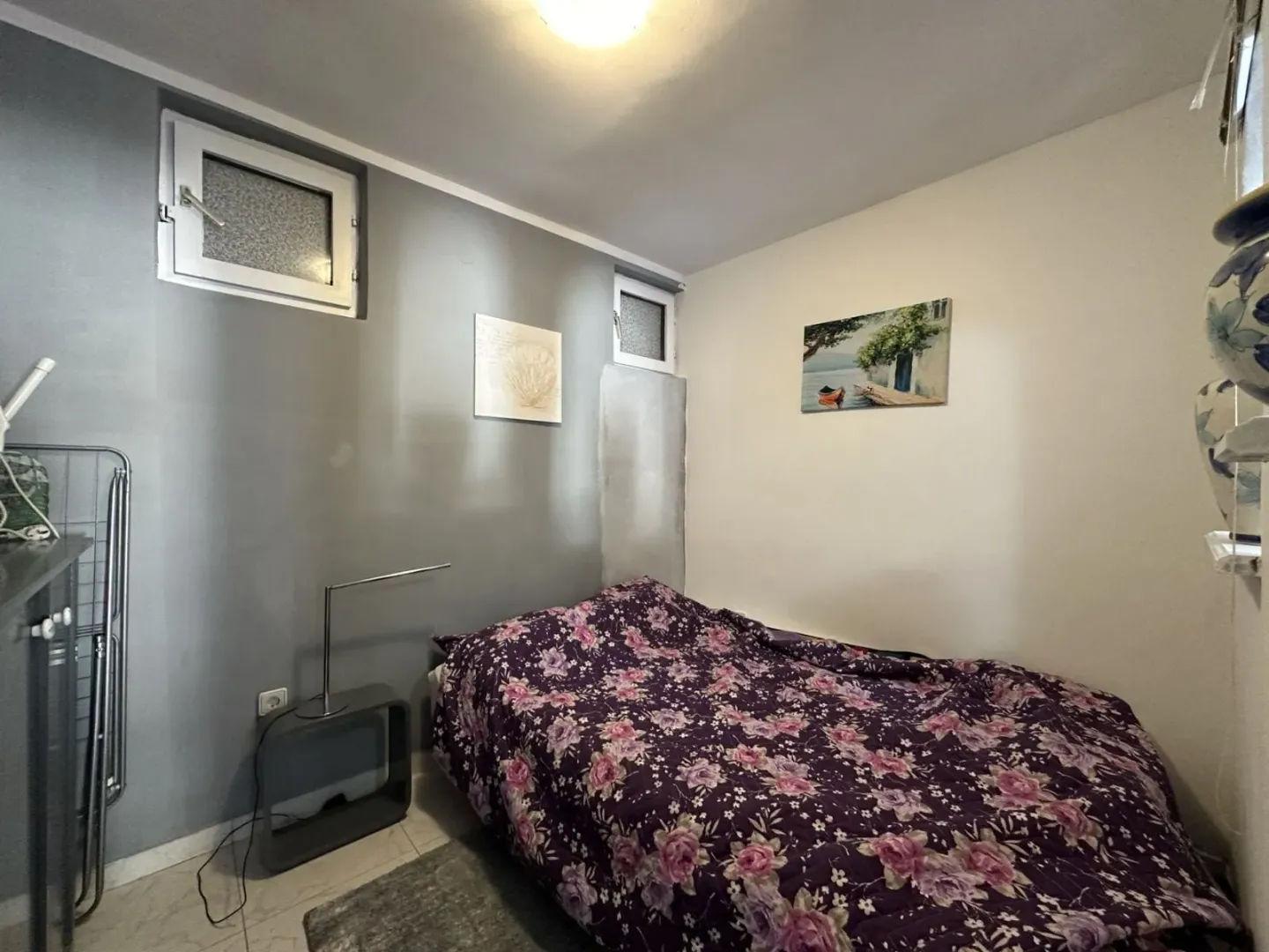 Small bedroom with a bed and decorative paintings on the wall.