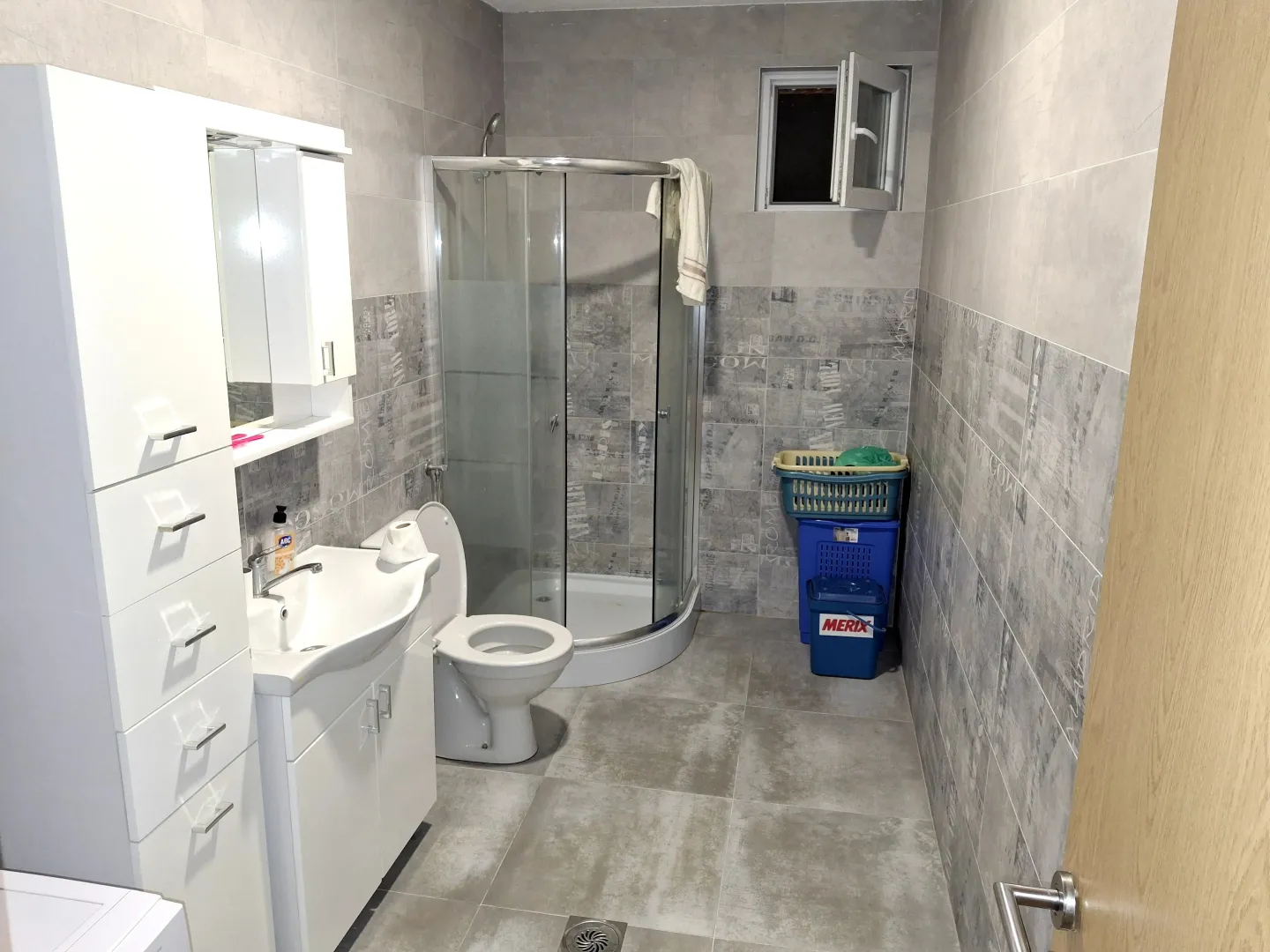 Savremeno opremljeno kupatilo sa tuš kabinom i bijelim sanitarijama.