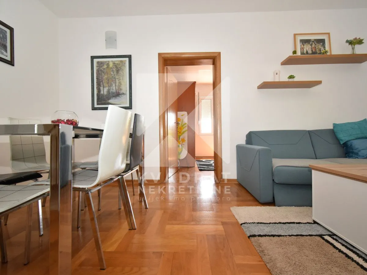 Living room with a sofa, dining table, and parquet flooring.