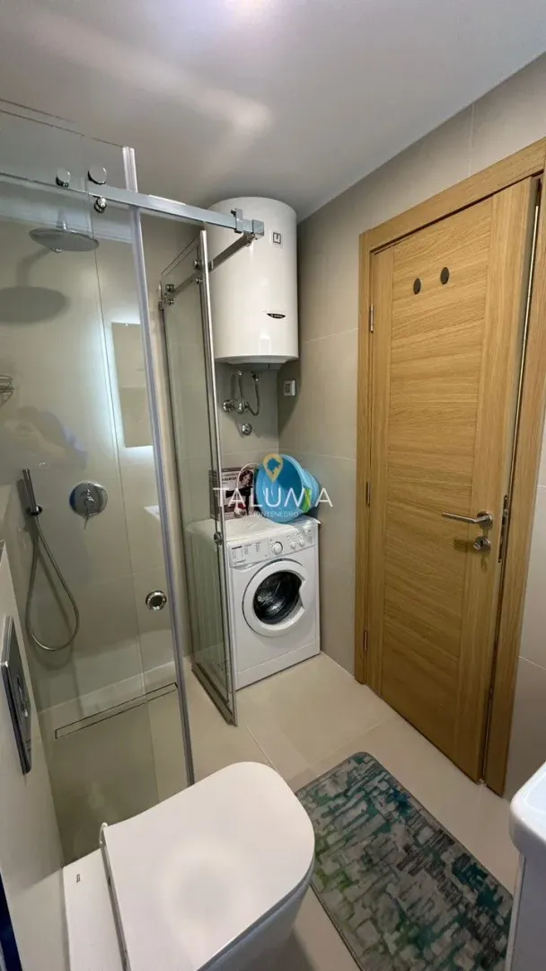 Modernly equipped bathroom with a shower cabin and washing machine.