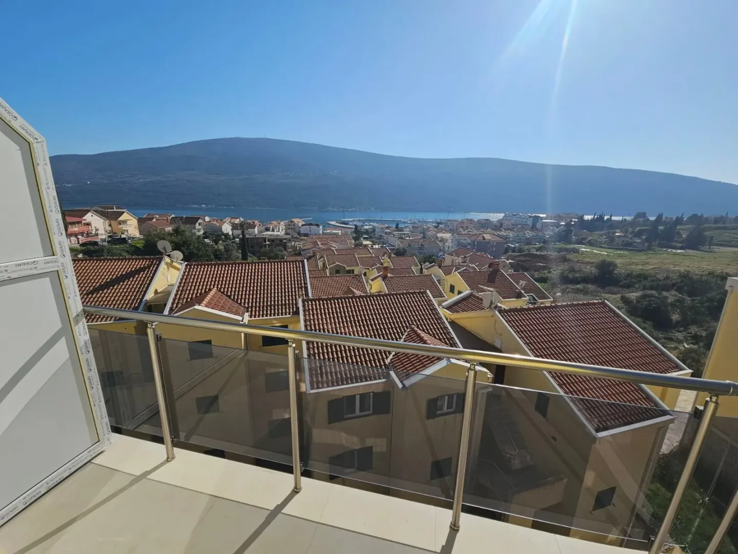 Pogled sa terase na naselje, more i planine u daljini.