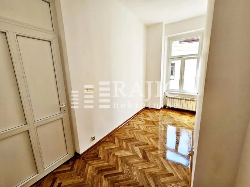 Empty room with parquet flooring and white walls.