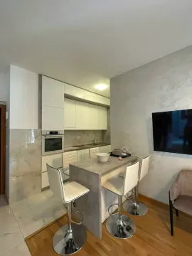 Modern kitchen with a bar and dining chairs, connected to the living room. - image 3