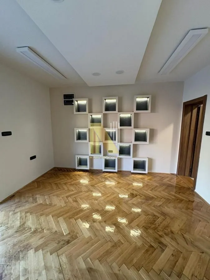 Empty room with wooden parquet flooring and decorative wall niches.