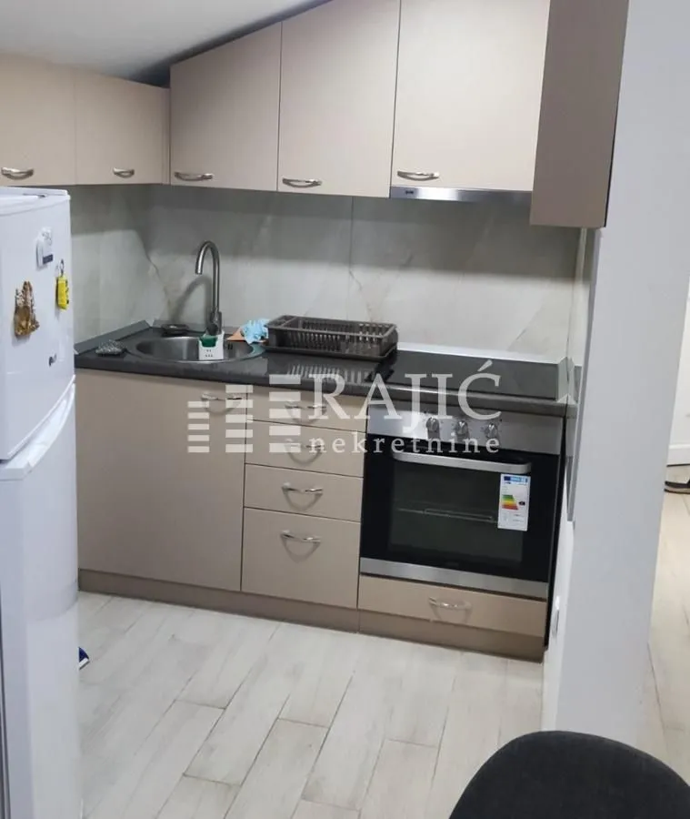 Small kitchen with beige cabinets and built-in appliances.