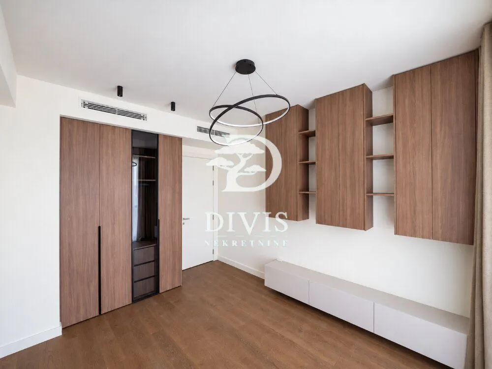 Modern bedroom with built-in wardrobes and wooden flooring.