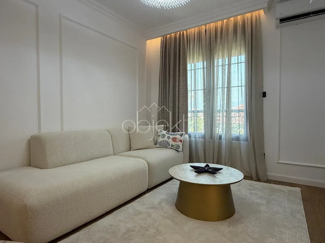 Living room with a comfortable sofa, coffee table, and window with curtains.