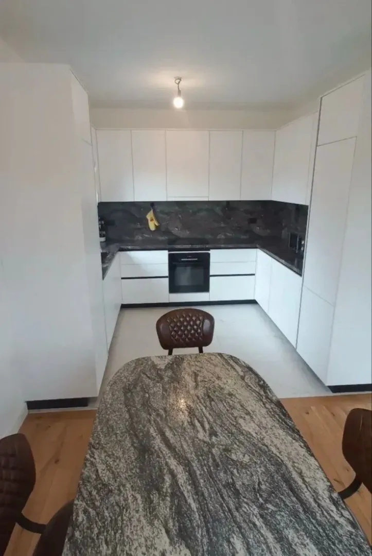 Modern kitchen with white cabinetry and a dining table.