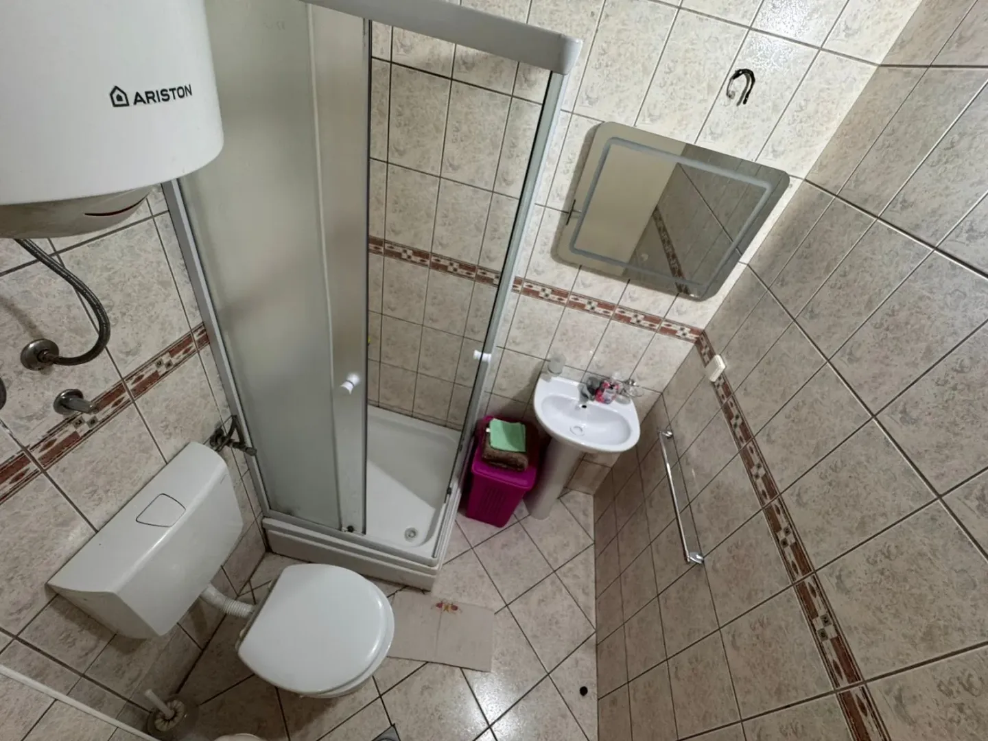 Small bathroom with a shower cabin, washbasin, toilet, and wall tiles.