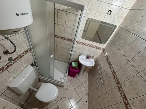 Small bathroom with a shower cabin, washbasin, toilet, and wall tiles. - image 8