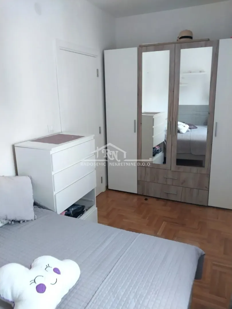 Furnished bedroom with a double bed, mirrored wardrobe, and chest of drawers.