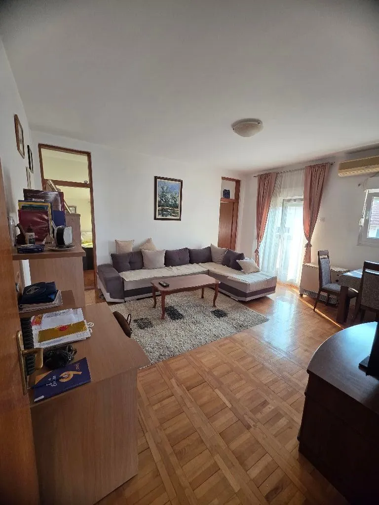 Prostrana dnevna soba sa garniturom za sedenje i trpezarijskim delom.