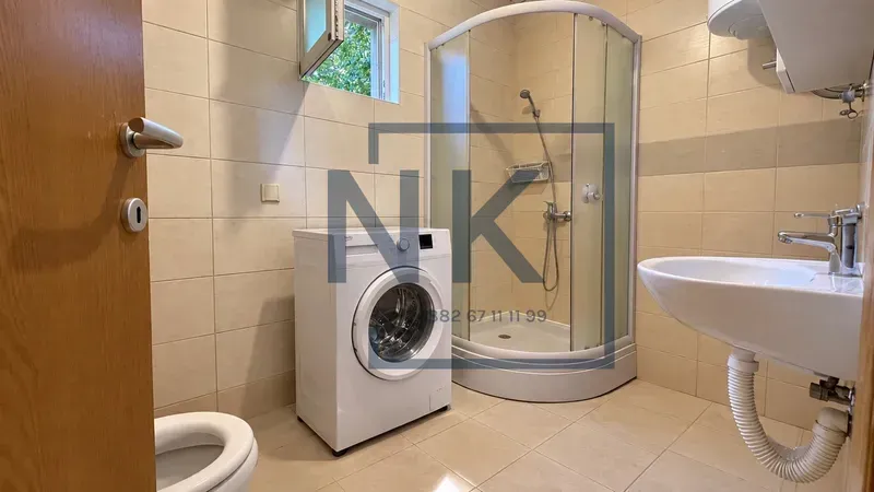 Bathroom equipped with a shower cabin, washbasin, toilet, and washing machine.