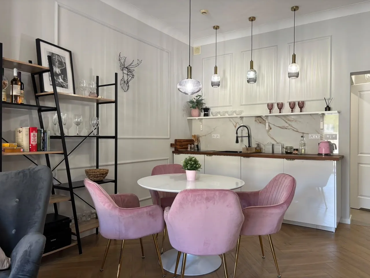 Moderna kuhinja sa trpezarijskim stolom i roze stolicama.