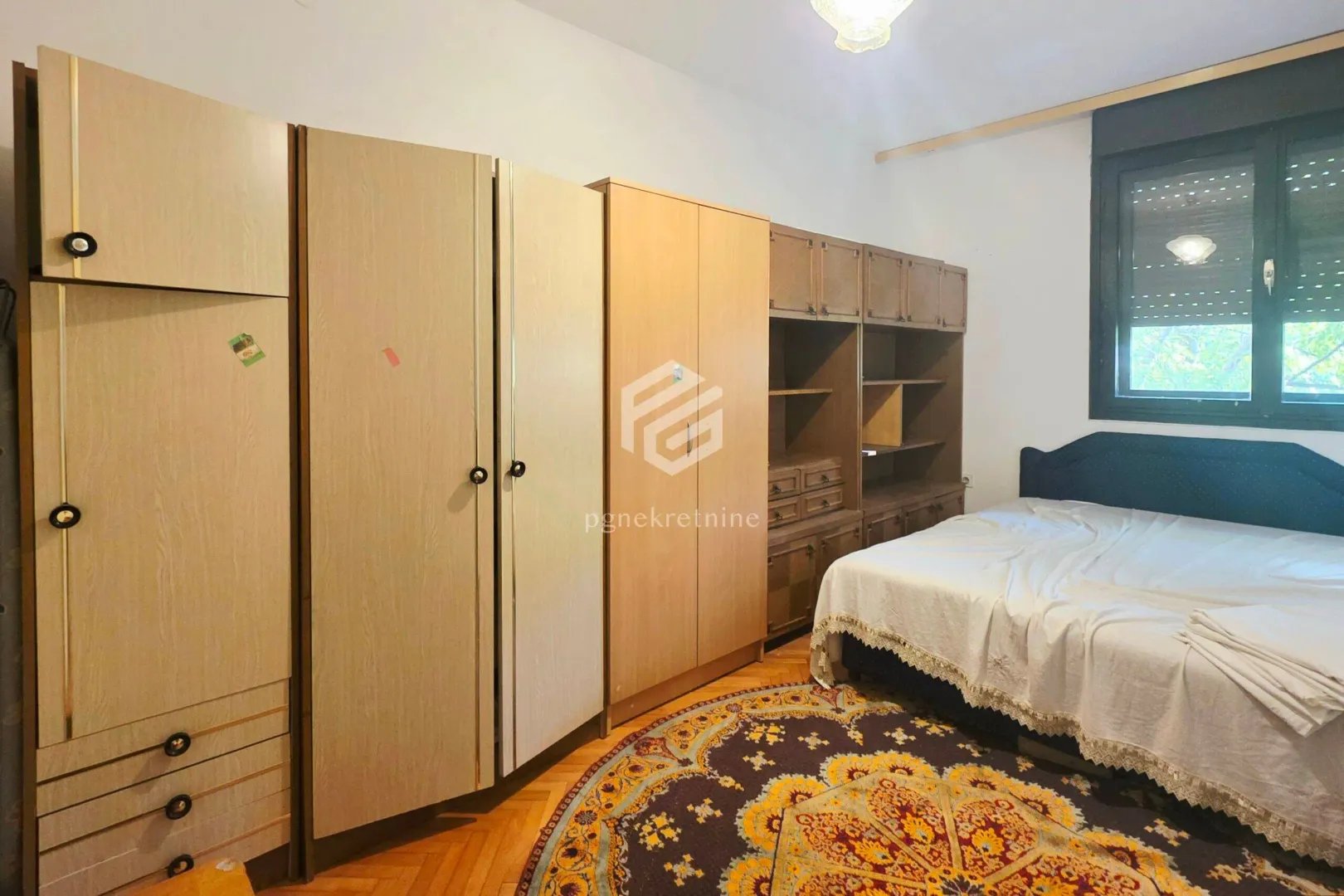 Furnished bedroom with large wardrobes, a bed, and a rug.