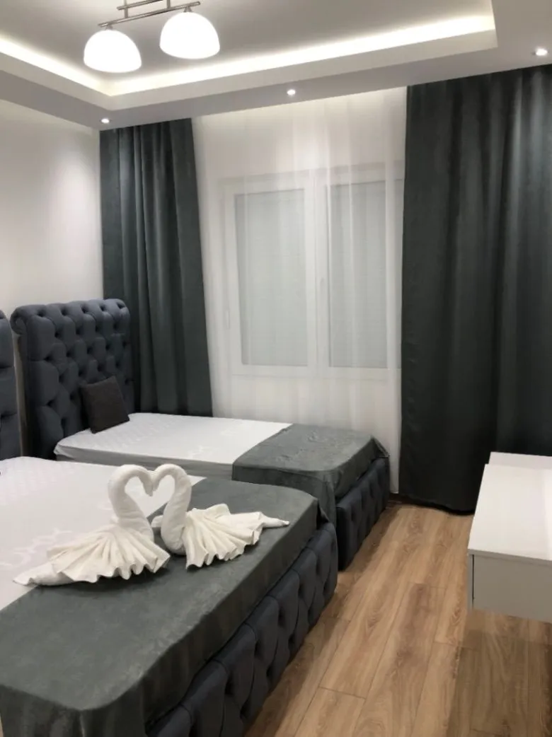 Modern bedroom with two single beds and decorative towels.