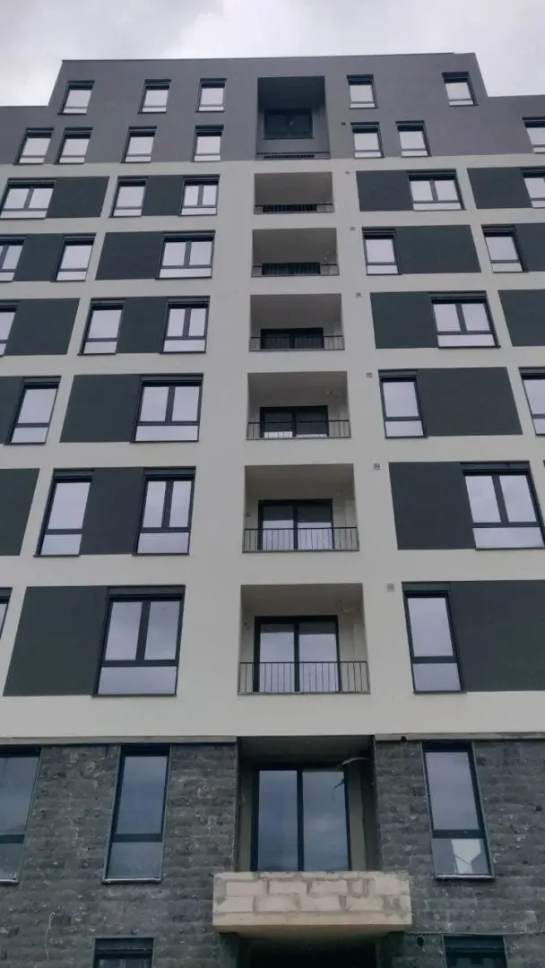 Moderna stambena zgrada sa sivom i bijelom fasadom.
