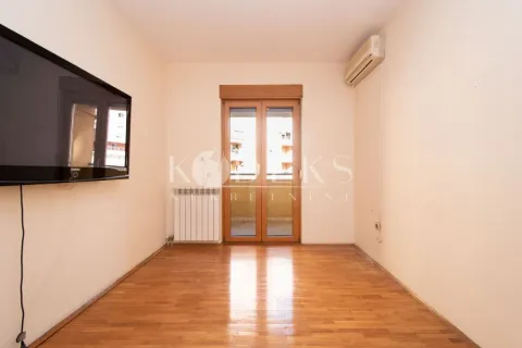 Empty living room with wooden flooring, wall-mounted TV, and balcony access. - image 6
