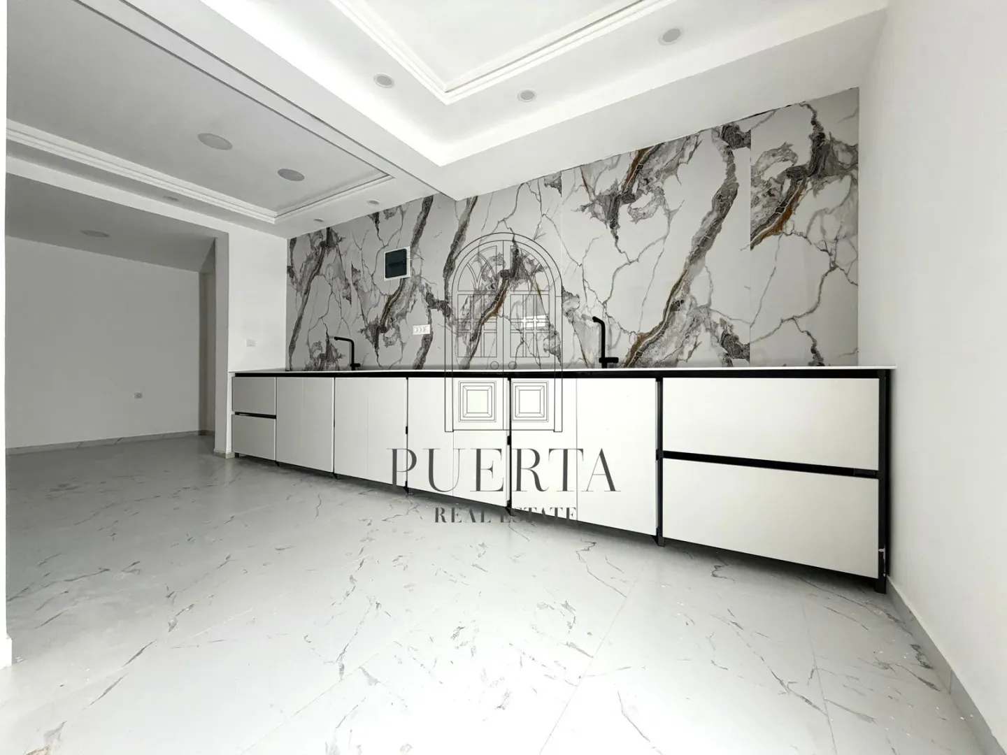 Modern kitchen with white cabinetry and marble wall panels.