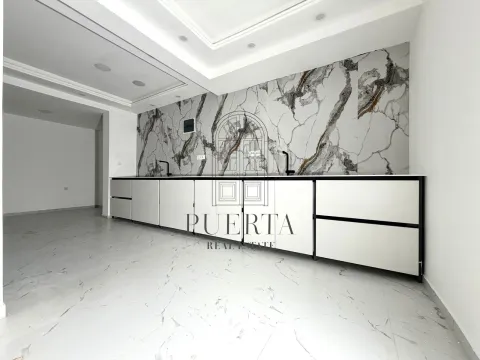 Modern kitchen with white cabinetry and marble wall panels. - image 10