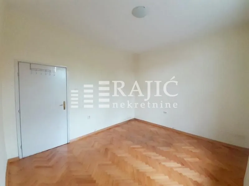 Empty room with parquet flooring and white walls.