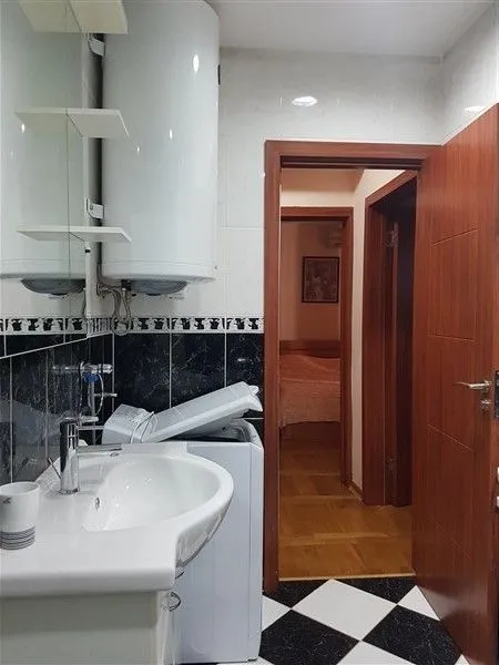 Kupatilo sa veš mašinom, bojlerom i pogledom ka hodniku.