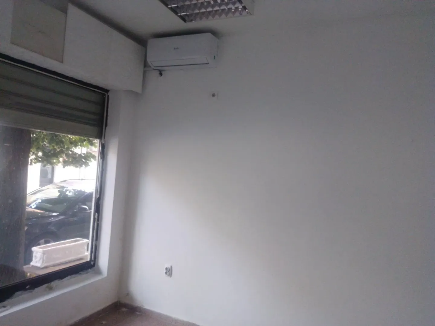 An empty interior space with white walls and an air conditioner.
