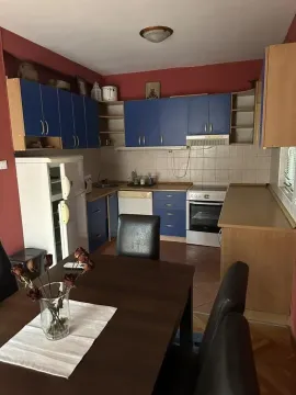 Kitchen with blue cabinets and a dining table in the foreground. - image 11