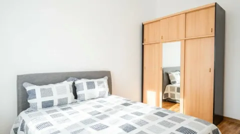 A bedroom with a double bed and a wooden wardrobe with a mirror. - image 2
