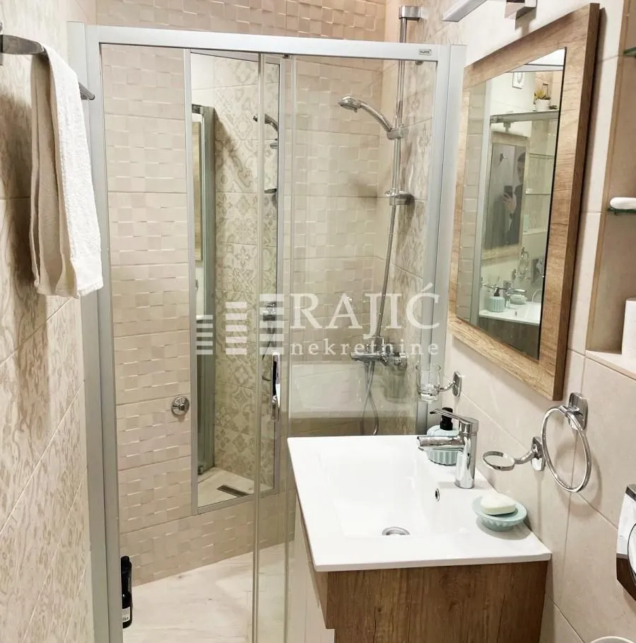Modern bathroom with shower cabin, washbasin and mirror.