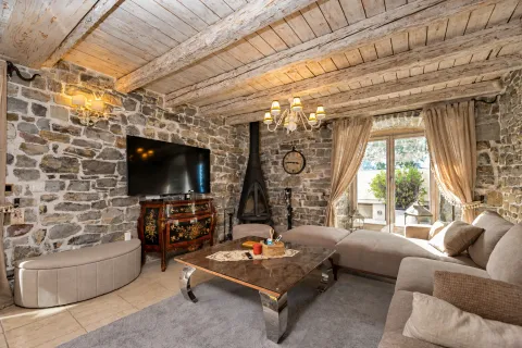 Living room with stone walls, wooden ceiling beams, and a fireplace. - image 2