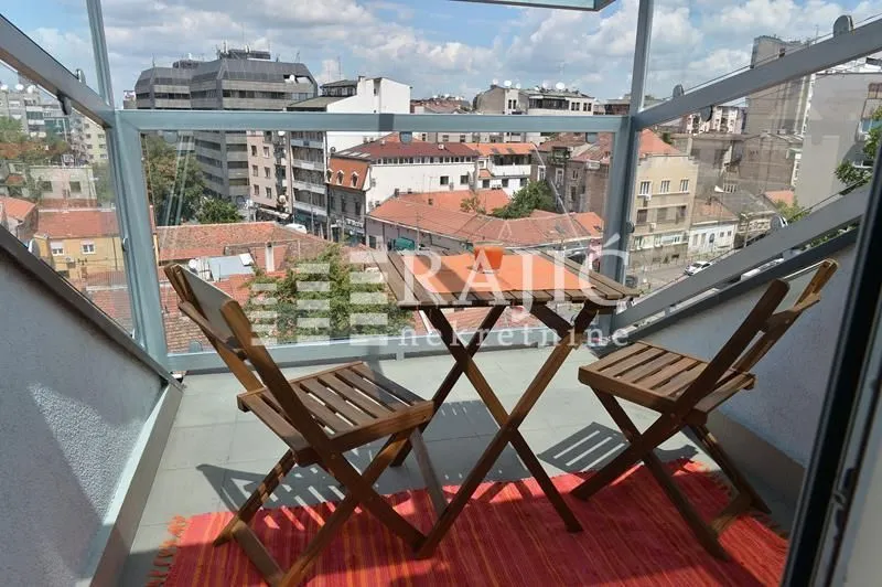 Enclosed balcony with a wooden table, chairs, and city view.