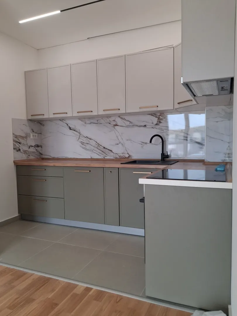 Modern kitchen with grey cabinets and a marble backsplash.