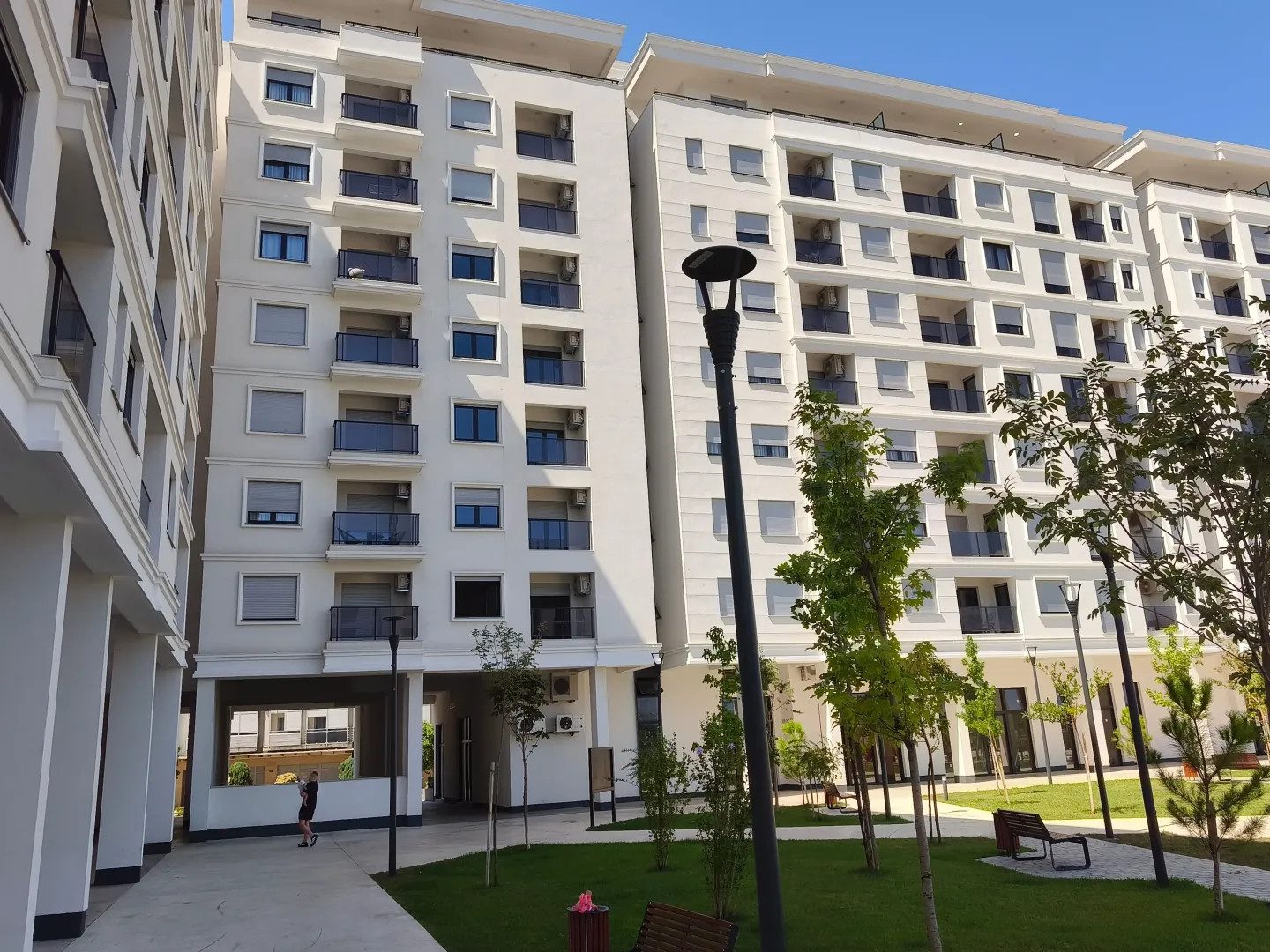 Fasada moderne stambene zgrade sa uređenim dvorištem.