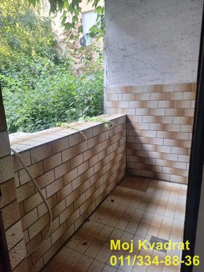 Manji popločani balkon sa pogledom na zelenilo.